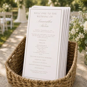 May include: A stack of white wedding programs with a thin brown border and elegant serif typography, featuring the text Welcome to the Wedding of Samantha and Steven, held in a woven tan wicker basket with a thick rope-like texture and pattern.