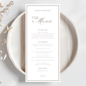 May include: A vertical rectangular menu card with a thin brown border, featuring the text Emily Oswald, The Menu, Starter, Entrees, and Dessert. The menu lists Waldorf Salad, Stuffed Chicken Breast, Braised Short Rib, Salmon, and Wedding Cake.