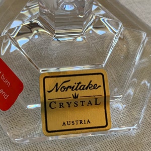 K&ouml;nnte beinhalten: Ein goldener Aufkleber mit schwarzem Text lautet "Noritake Crystal Austria" auf einem klaren Glasst&uuml;ck.
