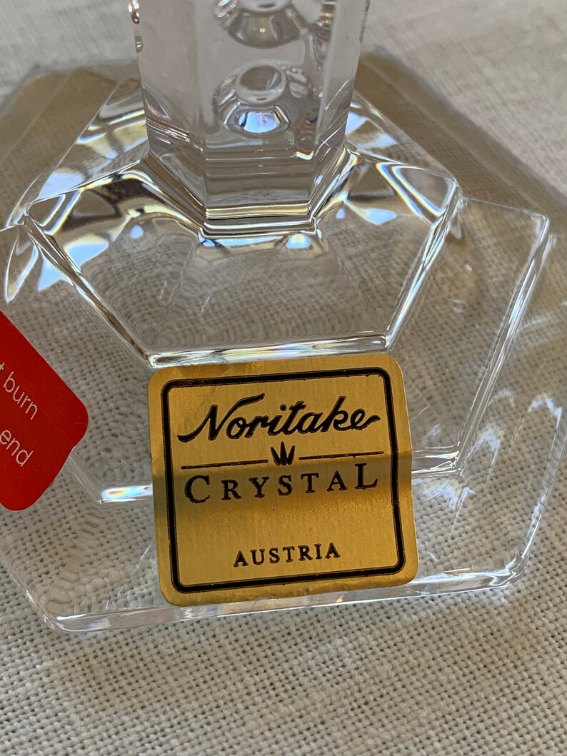 K&ouml;nnte beinhalten: Ein goldener Aufkleber mit schwarzem Text lautet "Noritake Crystal Austria" auf einem klaren Glasst&uuml;ck.