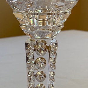 K&ouml;nnte beinhalten: Ein durchsichtiger Glas-Kerzenhalter mit geometrischem Design und einem dekorativen Muster aus Kreisen um die Basis.