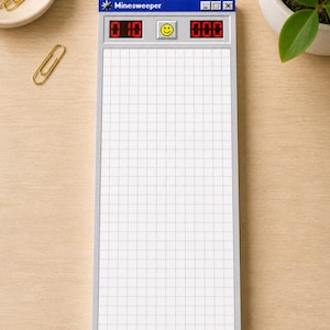 May include: A notepad designed to resemble the classic Minesweeper game interface. The top section features the game's title, a smiley face, and digital counters. The notepad has a grid pattern for writing and a gray border.