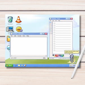 Op de afbeelding: Een witte pen ligt op een houten oppervlak naast een print met een computerinterface met open vensters. De vensters tonen een notitieblok, een tekenprogramma en een checklist. De afbeelding heeft een retro-esthetiek, die doet denken aan vroege 2000s computerinterfaces.