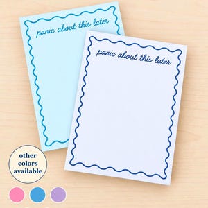 May include: Two rectangular notepads with a wavy blue border and the text "panic about this later" printed at the top. One notepad is light blue and the other is white. A circular graphic indicates other colors are available.
