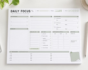 May include: A white daily focus planner notepad with black text and sage green accents. The layout includes sections for top priorities, notes, focus sessions, brain dump, tasks, self-care, contacts, reflection, and a time blocking schedule.