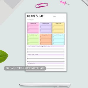 May include: A 50 page tear off notepad titled BRAIN DUMP with a date line and a main goal section. It features six colorful boxes for tasks like I need to call, email, text, do today, appointments, and follow up with, plus lined sections.