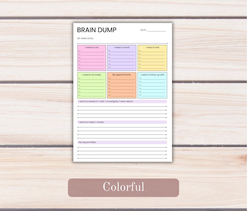 May include: A white paper planner page titled BRAIN DUMP with a date line and a main goal section. It features six colorful rectangular boxes for tasks, including pink, purple, yellow, green, orange, and blue, plus lined sections for notes.