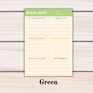 May include: A rectangular notepad with a light green header labeled BRAIN DUMP and a date field. The cream-colored paper is divided into six sections with colored lines and headings: MY TOP PRIORITIES, I NEED TO DO, I NEED TO CONTACT, I NEED TO SCHEDULE, I NEED TO PURCHASE, and FOR TOMORROW.