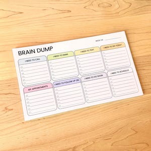 K&ouml;nnte beinhalten: Ein wei&szlig;er Brain Dump Notizblock mit Abschnitten f&uuml;r Aufgaben wie "I Need to Call", "I Need to Email" und "My Appointments". Der Notizblock hat ein einfaches Layout mit Kontrollk&auml;stchen f&uuml;r jede Aufgabe, konzipiert f&uuml;r die Wochenorganisation.