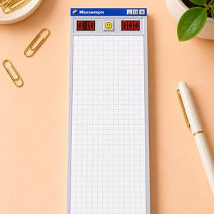 May include: A rectangular notepad designed to resemble the classic Minesweeper computer game interface. It features a blue title bar with the text Minesweeper, a yellow smiley face button, red digital counters, and a white grid pattern background.