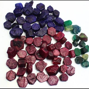 Può includere: Una collezione di pietre preziose sciolte, tra cui zaffiri blu, rubini rossi e smeraldi verdi. Le pietre preziose sono di varie dimensioni e forme, e alcune hanno un taglio sfaccettato.