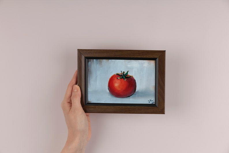 May include: A framed painting of a red tomato on a white background. The painting is signed "D.K. 2022" in the bottom right corner.