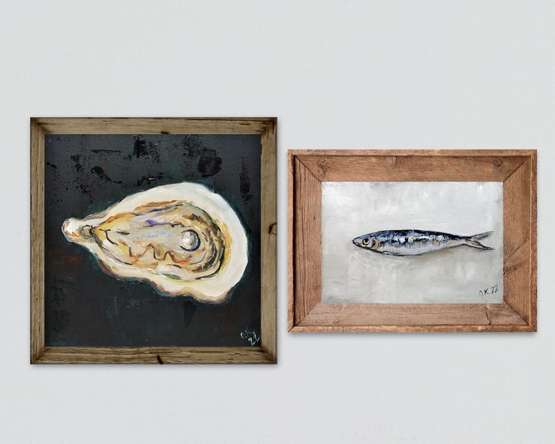 May include: Two framed paintings. One features a detailed oyster shell on a dark background. The other depicts a fish on a light background. Both paintings are in rustic wooden frames, adding a touch of natural charm to the artwork.