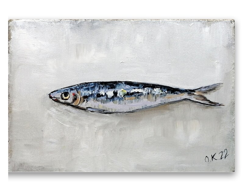 May include: A painting of a single silver sardine on a white background. The sardine is painted in a realistic style with details of its scales and fins. The artist's signature, "O.K.22", is in the bottom right corner.
