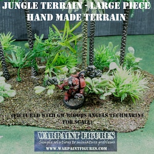 May include: A large piece of hand-made jungle terrain for tabletop gaming. The terrain features a variety of green plants and trees, and a miniature figure is standing in the centre. The text on the terrain reads "Jungle Terrain - Large Piece" and "Hand Made Terrain".
