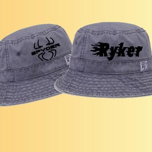 May include: Two gray bucket hats with black embroidered designs. One hat has a spider design with the word "Spyder" and the other has a flame design with the word "Ryker".