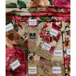 Puede incluir: Un conjunto de tela beige con un estampado floral de rosas en tonos rosa y rojo. El conjunto incluye una parte superior con detalles bordados, mangas y una dupatta de seda digital. El texto "ZN FABRICS" es visible.