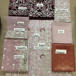 Op de afbeelding: Een meerdelige geborduurde kleding set in tinten bordeauxrood en roze. De set bevat een body, rug, mouwen, dupatta en broek. De stukken hebben ingewikkelde bloemenborduurwerk en versieringen.
