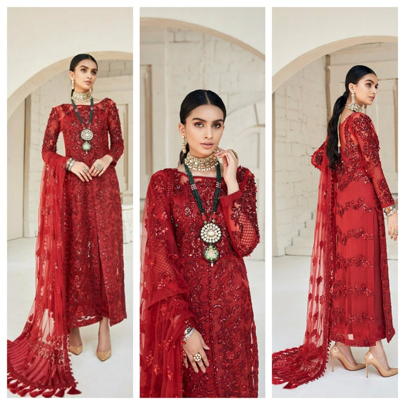 May include: A three-panel image of a red formal dress with intricate embroidery and a matching sheer shawl. The dress features long sleeves and a high neckline, with a slit up the front. The model is wearing gold-colored heels and jewelry.