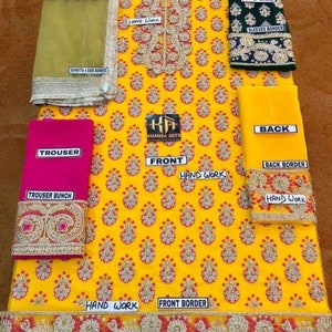 May include: A vibrant yellow embroidered outfit with floral patterns, featuring a pink trouser, green sleeves, and a maroon dupatta. The design includes intricate handwork and borders, with text labels indicating different parts.