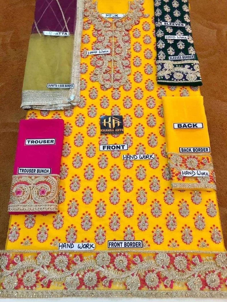 May include: A vibrant yellow embroidered outfit with floral patterns, featuring a pink trouser, green sleeves, and a maroon dupatta. The design includes intricate handwork and borders, with text labels indicating different parts.