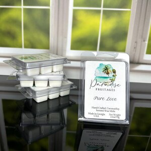 Peut inclure: Un empilement de quatre contenants transparents de cire &agrave; fondre avec un seul contenant de cire &agrave; fondre &eacute;tiquet&eacute; "Paradise Fruitages Pure Love" avec une sc&egrave;ne d'&icirc;le tropicale. L'&eacute;tiquette indique &eacute;galement "Hand-Crafted Coconut/Soy Scented Wax Melts, Made in Georgia USA, Net Weight 2.5oz/70g."