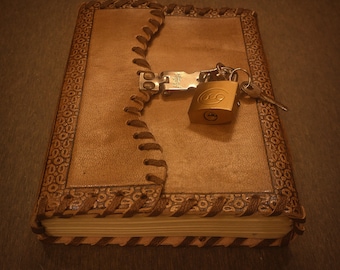 May include: A brown leather-bound journal with a lock and key. The journal has a decorative border and a flap that closes with a clasp.