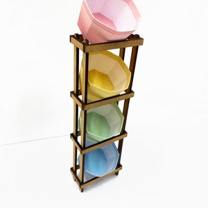 May include: A wooden stand with four shelves, each holding a pastel-colored ceramic bowl. The bowls are pink, yellow, green, and blue.