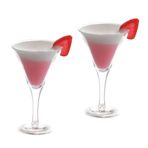 May include: Two pink and white layered cocktails in martini glasses with red plastic swizzle sticks.