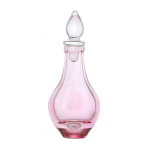 May include: A pink glass bottle with a clear glass stopper. The bottle has a rounded, pear-shaped body and a wide, flat base.