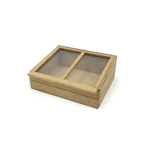 Könnte beinhalten: Eine Holzkiste mit zwei klaren Glasscheiben oben. Die Kiste ist aus hellbraunem Holz und hat ein schlichtes Design.