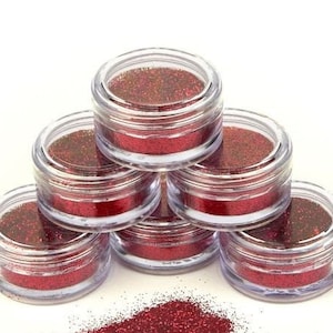 May include: Six small clear jars filled with red glitter, stacked in a pyramid shape.