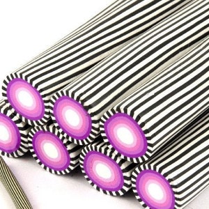 Könnte beinhalten: Nahaufnahme von mehreren schwarz-weiß gestreiften Polymer Clay-Stäben mit einem rosa-weißen Ombre-Querschnitt. Die Stäbe sind übereinander gestapelt.