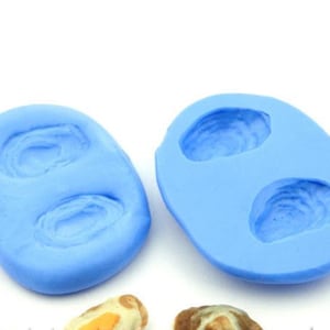 May include: Two blue silicone moulds for making two oyster shapes. Each mould has a detailed impression of an oyster shell.