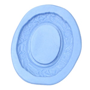 May include: A light blue silicone mold with a raised oval design in the center. The oval is surrounded by a decorative floral border.
