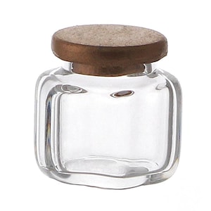 May include: A clear glass jar with a square shape and a wooden lid. The lid is a light brown colour.