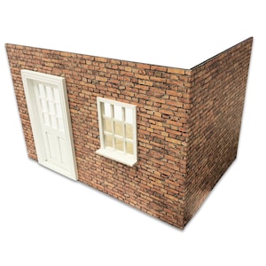 Könnte beinhalten: Eine Miniatur-Ecke einer Backsteinmauer mit einer weißen Tür und einem Fenster. Die Tür hat mehrere rechteckige Paneele, und das Fenster hat ein Gittermuster. Das Mauerwerk ist eine Mischung aus Braun- und Rottönen.