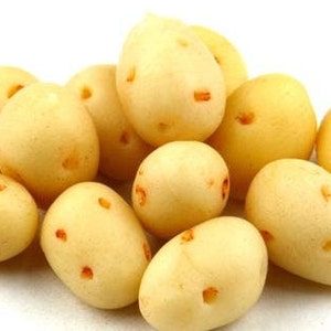 Könnte beinhalten: Eine Gruppe kleiner, blassgelber Kartoffeln mit rotbraunen Flecken. Die Kartoffeln liegen auf einer weißen Oberfläche.