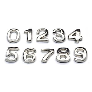 May include: Ten silver metal number charms, each with a different number from 0 to 9. The numbers are all the same size and style.