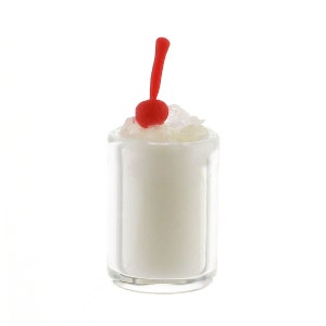 Könnte beinhalten: Ein Mini-Milchshake in einem klaren Glas, garniert mit Schlagsahne und einer leuchtend roten Kirsche. Der Milchshake hat eine cremeweiße Farbe, und das Glas ist zylindrisch. Die Kirsche hat einen langen, gebogenen Stiel.