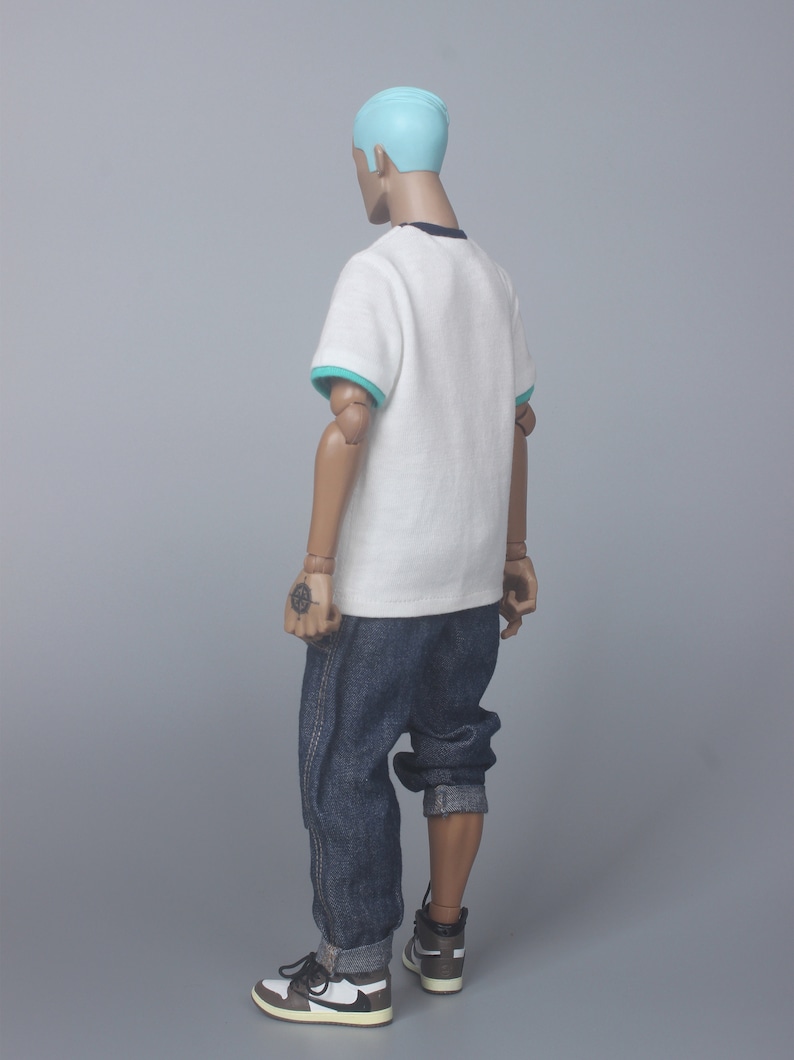 May include: A white t-shirt with a teal trim around the collar and sleeves. The t-shirt is being worn by a person with blue hair and blue jeans. The person is wearing white and brown sneakers.