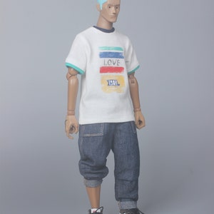 May include: A white t-shirt with a colorful striped design and the word "LOVE" printed on the front. The shirt also has the text "1981" printed on the front. The person is wearing blue jeans and white sneakers.