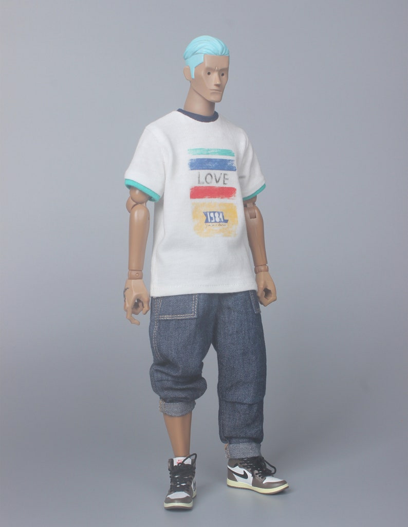 May include: A white t-shirt with a colorful striped design and the word "LOVE" printed on the front. The shirt also has the text "1981" printed on the front. The person is wearing blue jeans and white sneakers.
