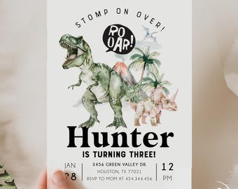 Puede incluir: Una invitación blanca con una ilustración de dinosaurio verde y marrón. El texto dice "Stomp on Over!" con un globo de diálogo que dice "Roar!" y "Hunter cumple tres años!" con la fecha y la hora de la fiesta.