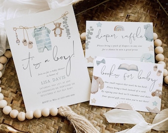 May include: It's a boy! Baby shower invitation with a blue and white striped onesie hanging on a clothesline with a teddy bear and eucalyptus leaves. The invitation includes the text "It's a boy!" and the name "Lisa Davis".