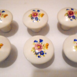 Pu&ograve; includere: Sei pomelli per mobili in ceramica bianco sporco con un motivo floreale con fiori rosa, blu e gialli. I pomelli hanno una forma rotonda e sono adatti per mobili o decorazioni.