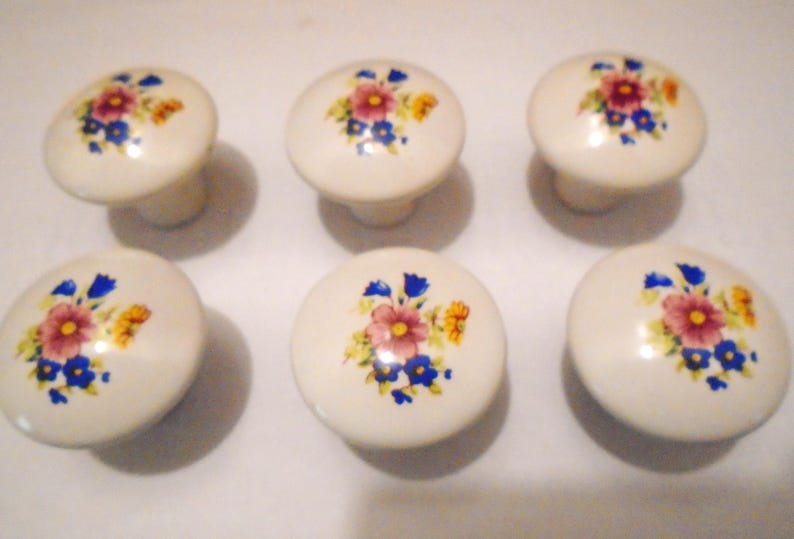 Pu&ograve; includere: Sei pomelli per mobili in ceramica bianco sporco con un motivo floreale con fiori rosa, blu e gialli. I pomelli hanno una forma rotonda e sono adatti per mobili o decorazioni.