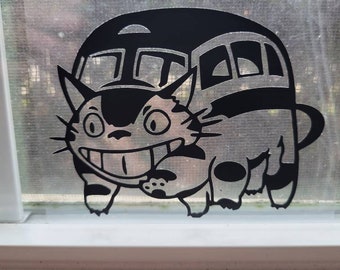 May include: Black and white vinyl sticker of a cat carrying a house on its back. The cat is smiling and has large eyes. The house has windows and a rounded roof.