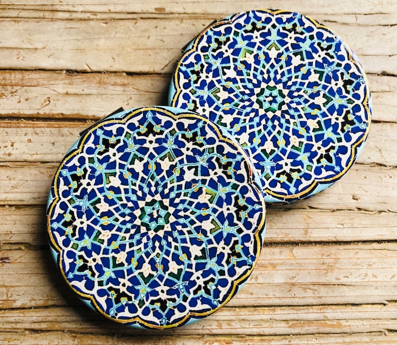 May include: Two round blue and white ceramic coasters with intricate geometric patterns. The coasters have a light blue background with white and dark blue details.