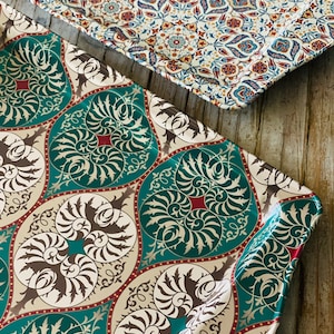 May include: Two decorative trays with intricate patterns. The top tray has a white background with blue, red, and brown floral designs. The bottom tray has a teal background with brown and white floral designs.